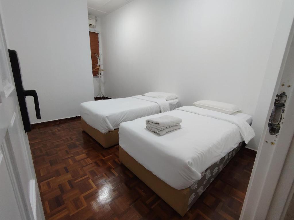 关丹YNY Guest House的配有白色墙壁和木地板的客房内的两张床