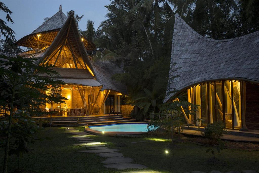 une maison avec une piscine devant elle la nuit dans l'établissement Cacao House Eco-Luxury Family Home by IBUKU near Green School Bali, à Bringkit