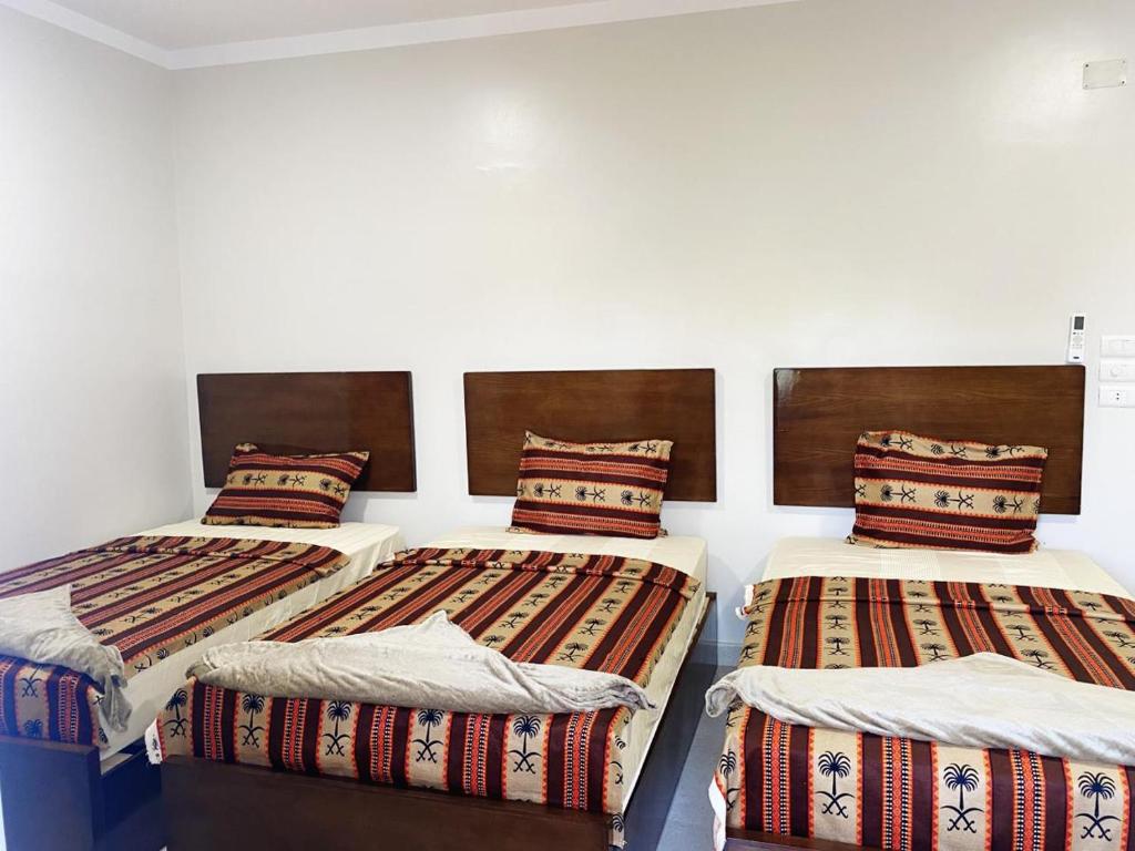 3 Betten in einem Zimmer mit weißen Wänden in der Unterkunft nubian yellow desert in Assuan