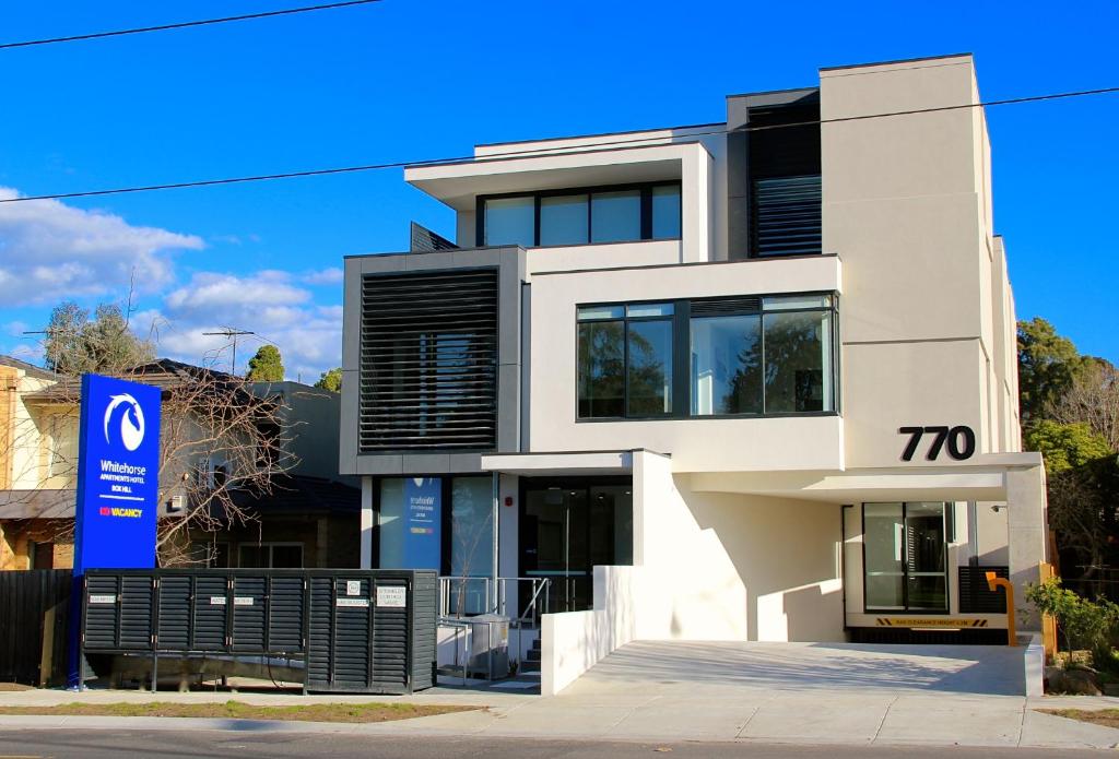 a white house with a sign in front of it at Whitehorse Apartments Hotel in Box Hill