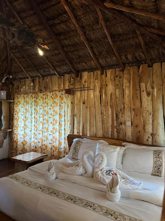 a bedroom with a large white bed with wooden walls at Podocarpus Cottages -02 in Naro Moru