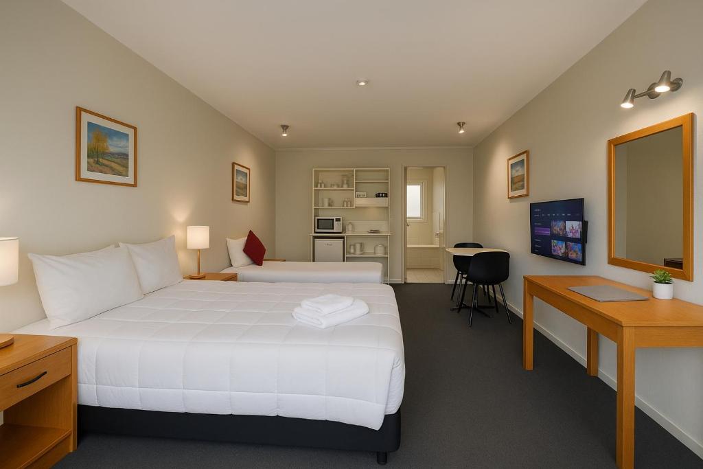 a hotel room with two beds and a desk at Karaka Tree Motel in Taupo