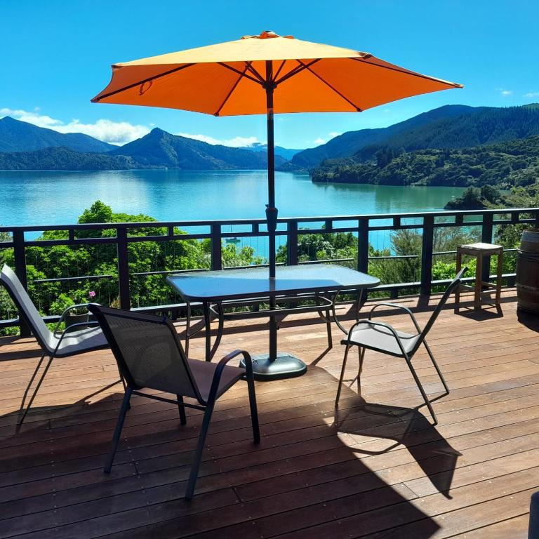 a table and two chairs and an umbrella on a deck at Moetapu Scenic Retreat in Linkwater