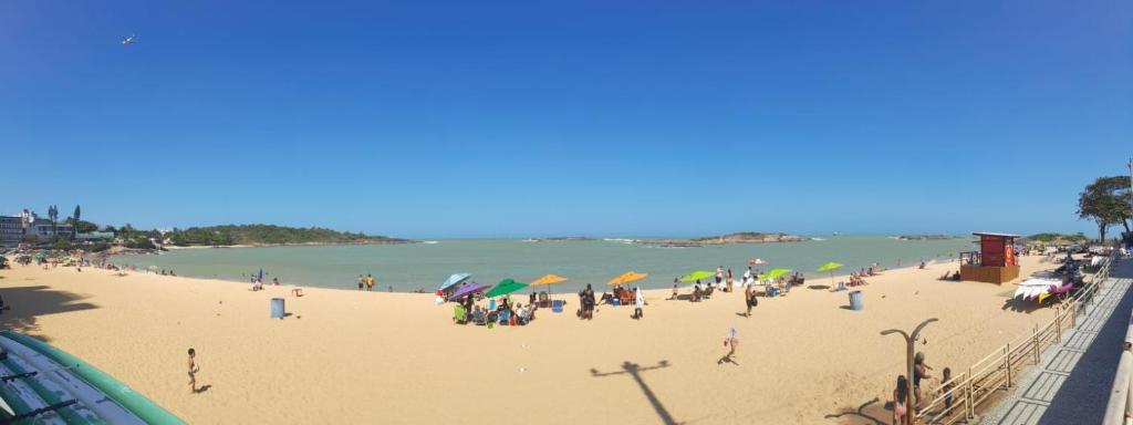 a group of people on a beach with umbrellas at Recanto aconchegante próximo ao mar in Vila Velha