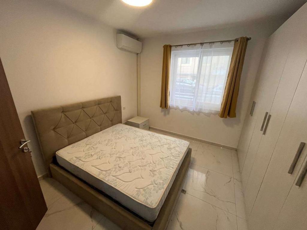 Un dormitorio pequeño con una cama y una ventana. en Qawra Seaside Birch Leaf, en St Paul's Bay