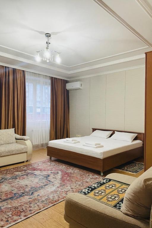 une chambre avec un grand lit et un canapé dans l'établissement 57 Очень теплая уютная квартира возле Байтерека с 2 большими кроватями и с 2 диванами для 1-6 человек, à Astana