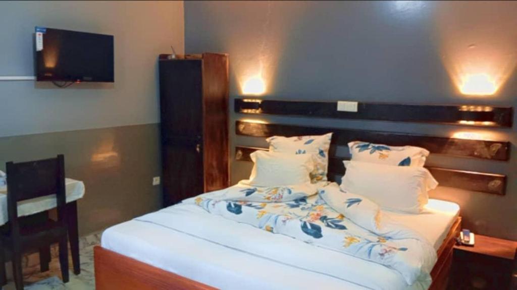 Un dormitorio con una cama y una mesa con televisión. en Sunrise Center Bonapriso, en Douala