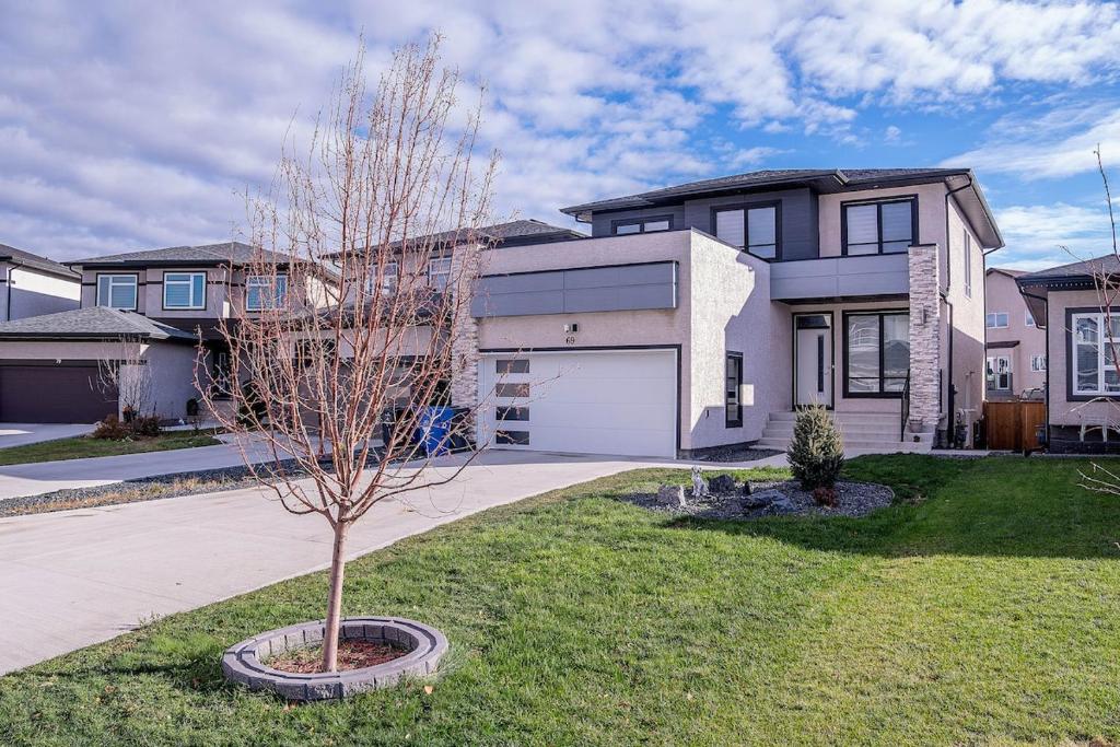 a tree in a yard in front of a house at Beautiful Brand New 2BR Suite with Private Entrance and free on-site parking in Winnipeg