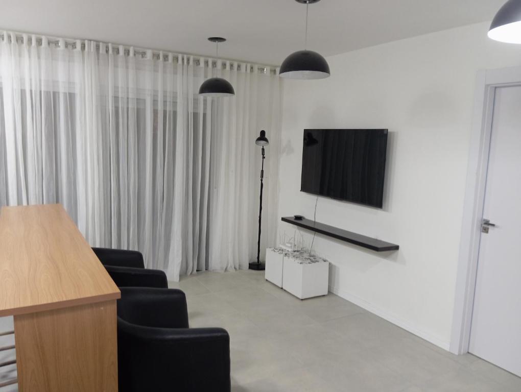 a living room with two chairs and a flat screen tv at Apartamento com piscina, terraço, churrasqueira e estacionamento in Pelotas