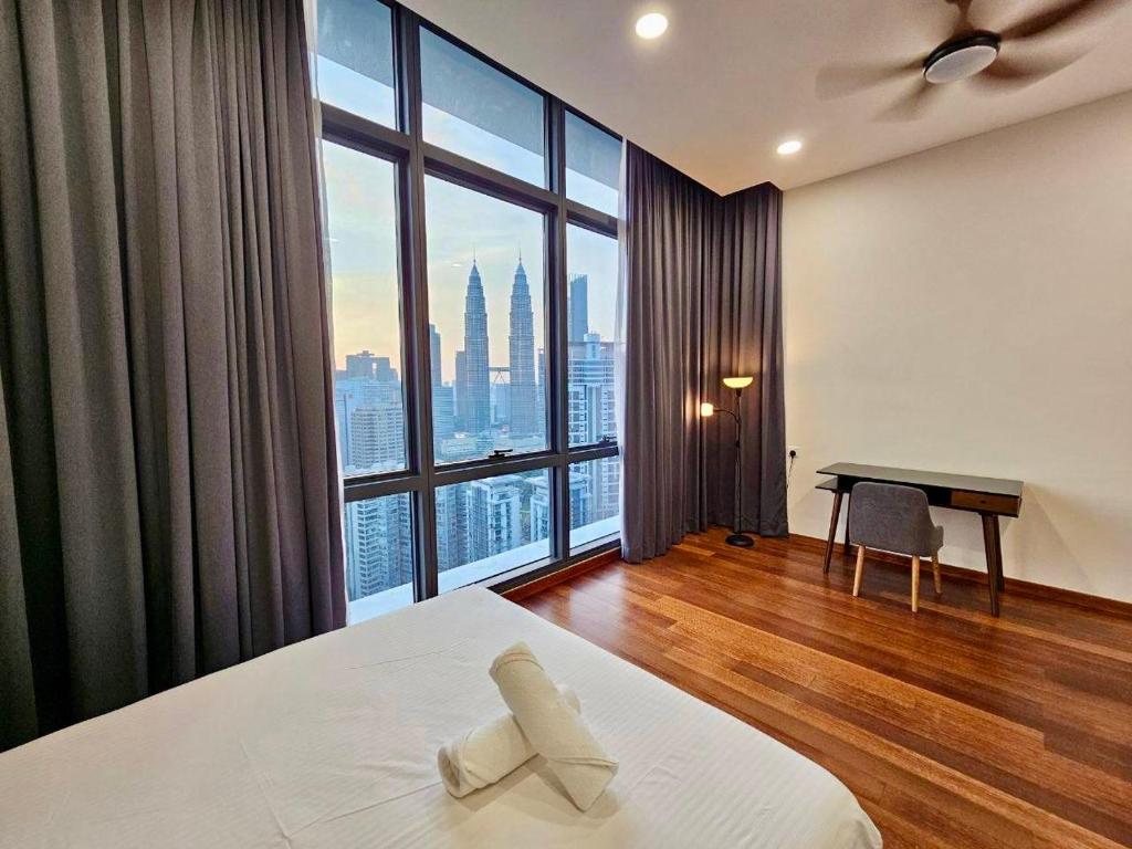 une chambre avec un lit et un bureau et une grande fenêtre dans l'établissement Pearl Suites At The Manor Kuala Lumpur, à Kuala Lumpur