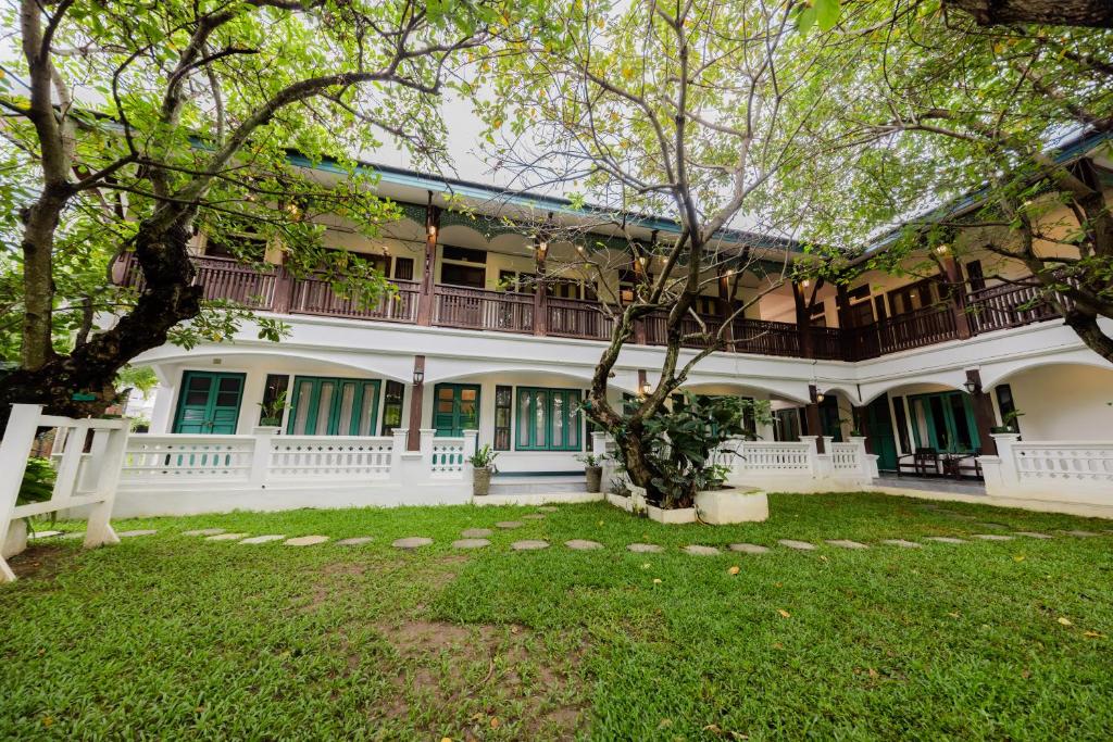 ein großes weißes Gebäude mit einem Baum im Hof in der Unterkunft Teewana Resort ChiangMai in Chiang Mai
