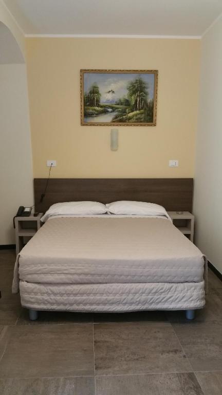 ジェノヴァにあるHotel Tommaseoのベッドルーム1室(ベッド1台付)が備わります。壁に絵が飾られています。
