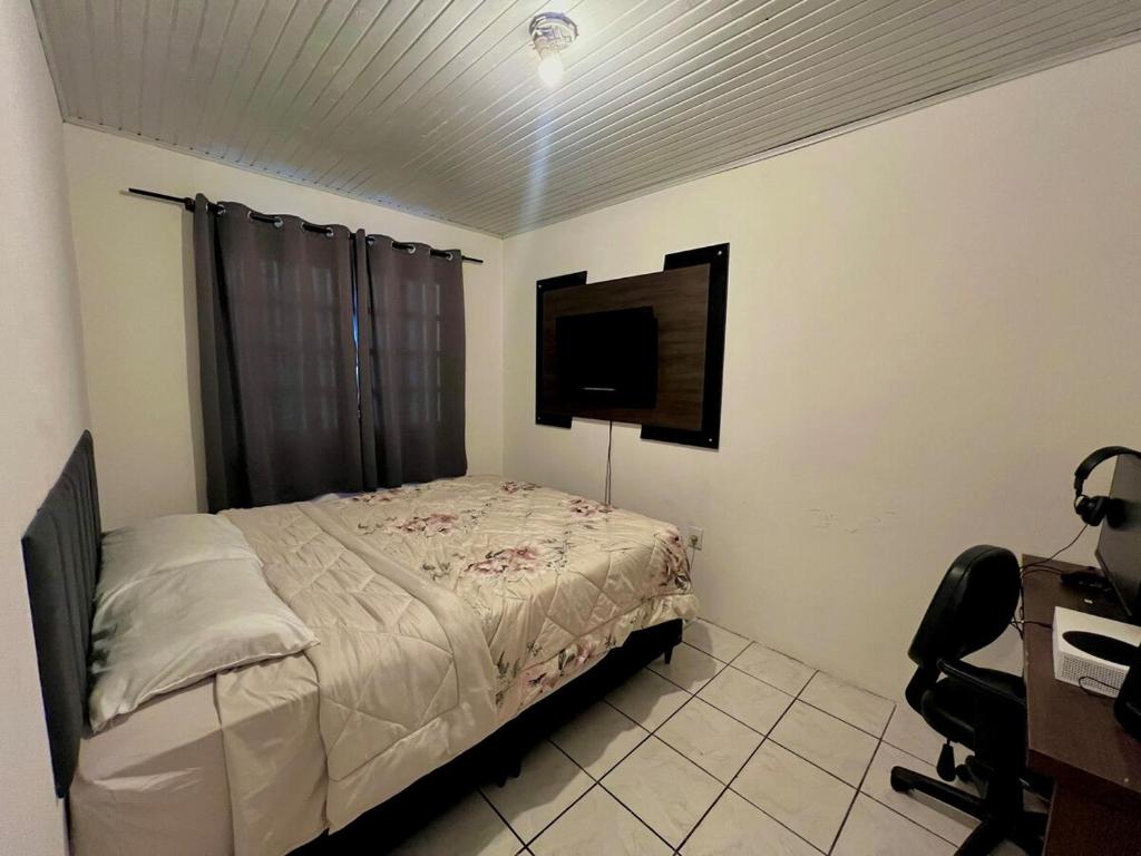 a bedroom with a bed and a desk and a television at Casa no centro de Torres in Torres