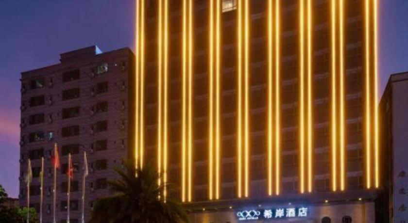 un grand bâtiment avec des lumières sur le côté dans l'établissement Xana Hotelle· Dongguang Chang'An Binhaiwan Jian'An Road, à Hongmei