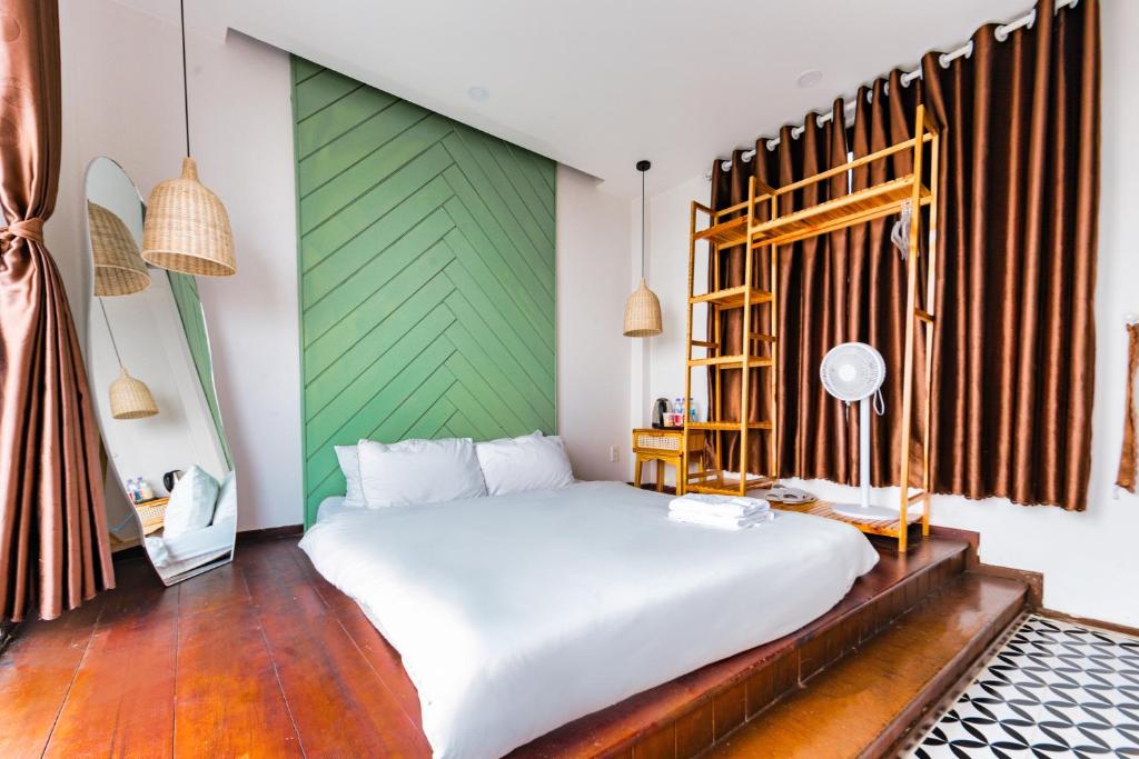 a bedroom with a white bed and a green wall at Beyoung Hotel Dalat in Da Lat