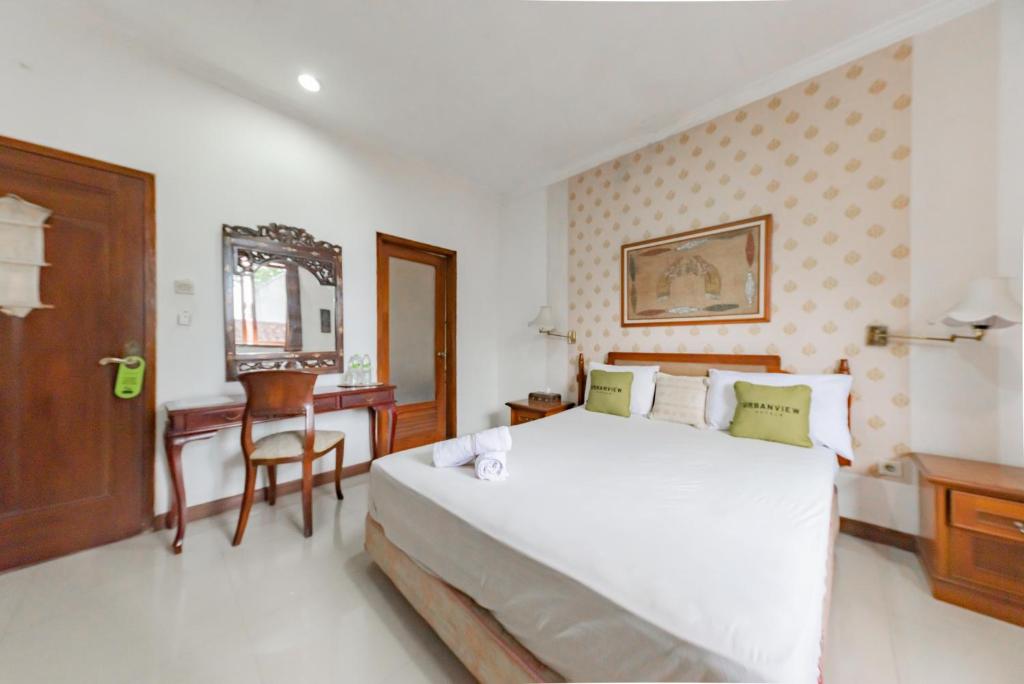 a bedroom with a large white bed and a desk at Urbanview De Ethnic Hotel Bandung by RedDoorz in Bandung
