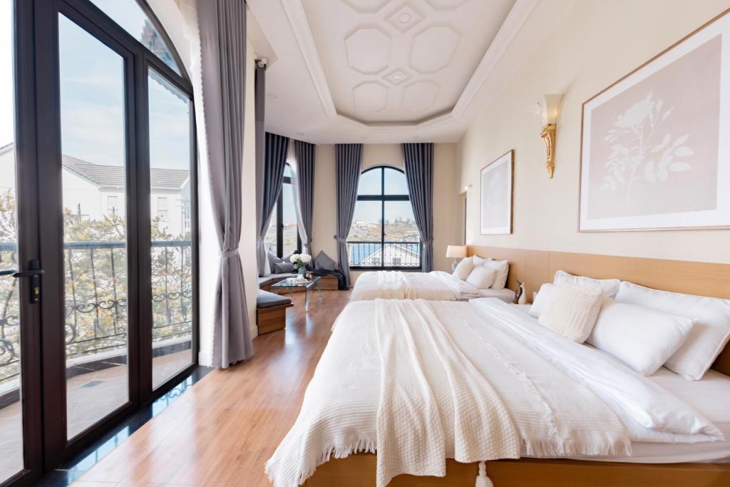 two beds in a bedroom with large windows at An Nhiên Hotel & Villa Da Lat in Da Lat