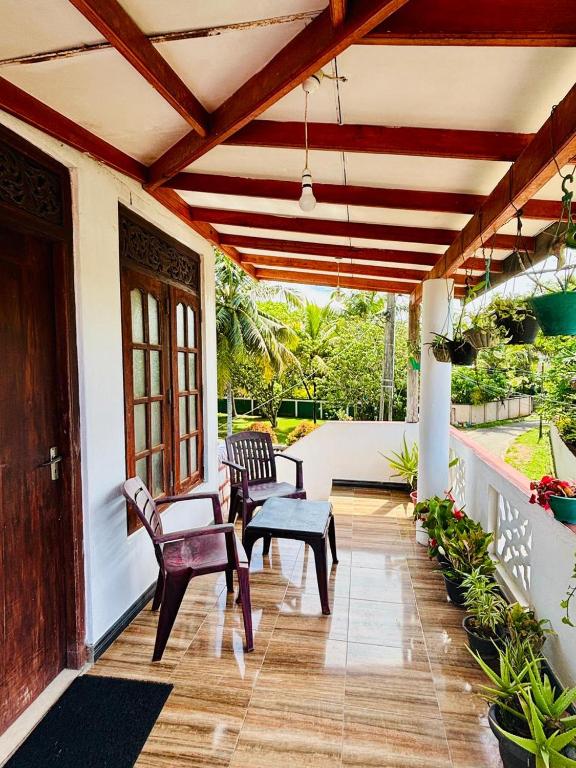 a porch with two chairs and a bench on a house at Nimsara Lodge in Hikkaduwa