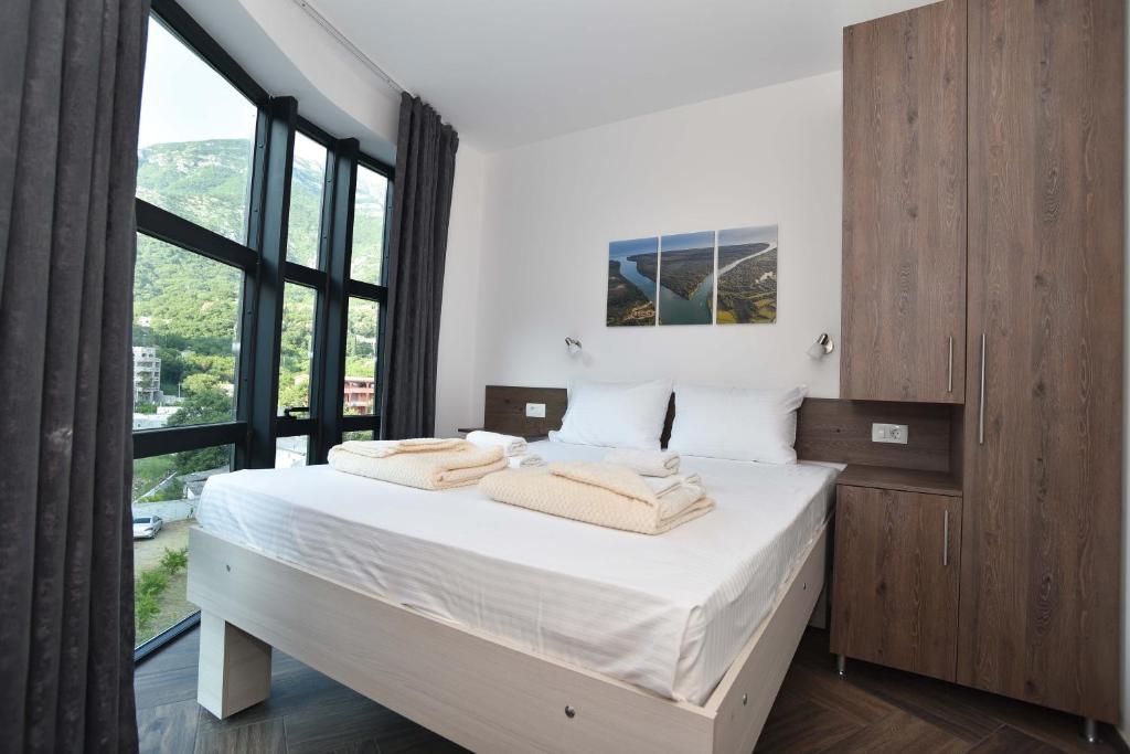 um quarto com uma cama com lençóis brancos e uma grande janela em Lux Čanj em Čanj