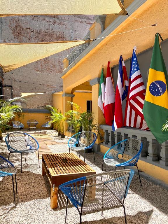 a group of tables and chairs with flags on a building at Roomies Hostel - Roma in Mexico City