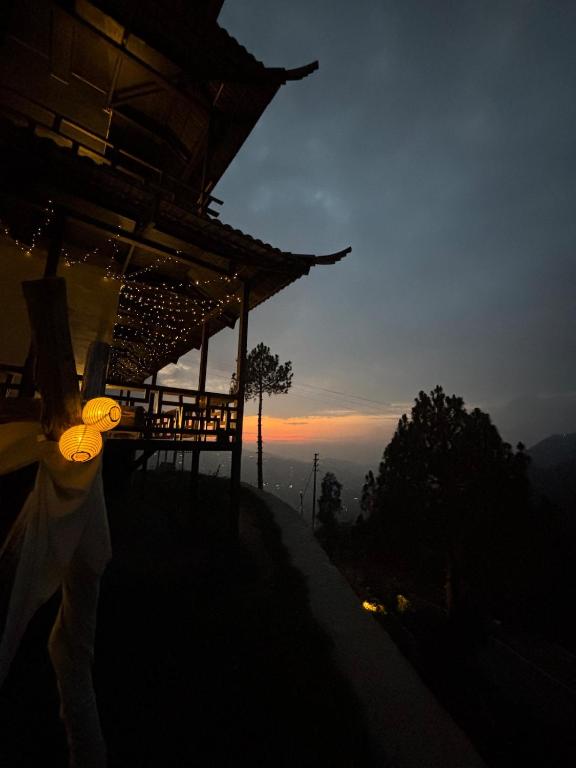 a building on top of a hill with the sunset at The Wild Sakura in Mukteshwar