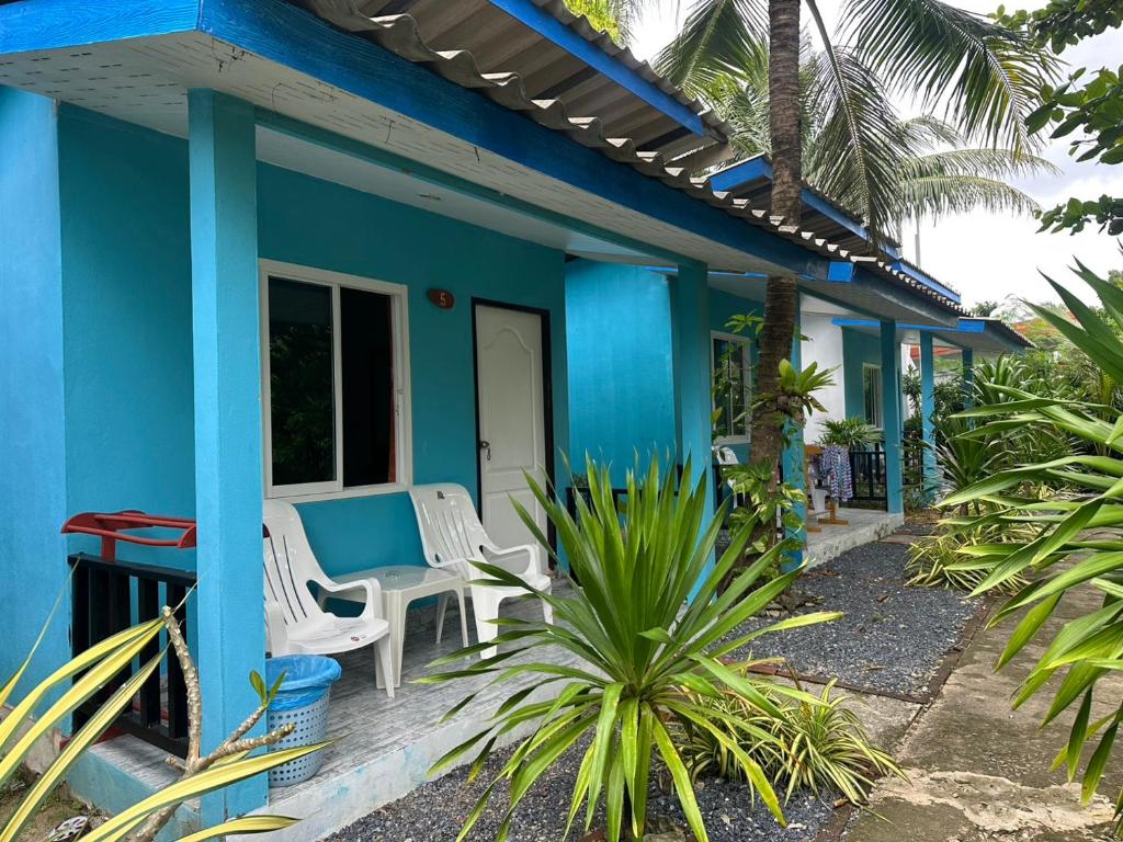 une maison bleue avec des chaises blanches et une table dans l'établissement Lanta bluewave Bungkalow, à Phra Ae beach