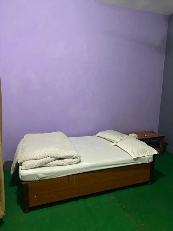 Cama en habitación con pared púrpura en Hotel Bajhang, en Bahāsi