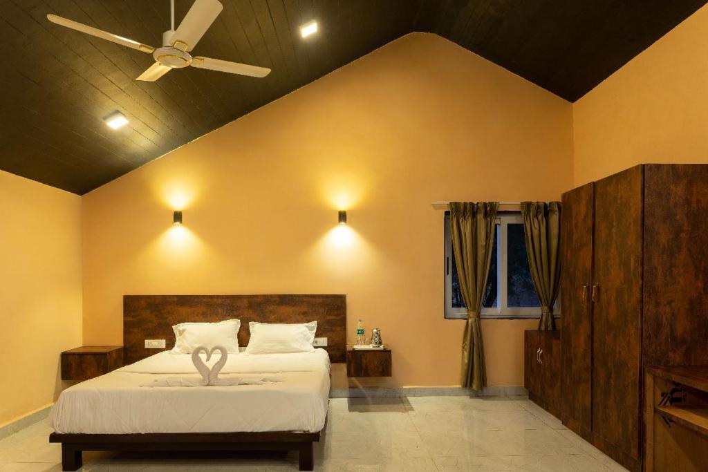 a bedroom with a bed and a ceiling fan at Green view resort in Dandeli