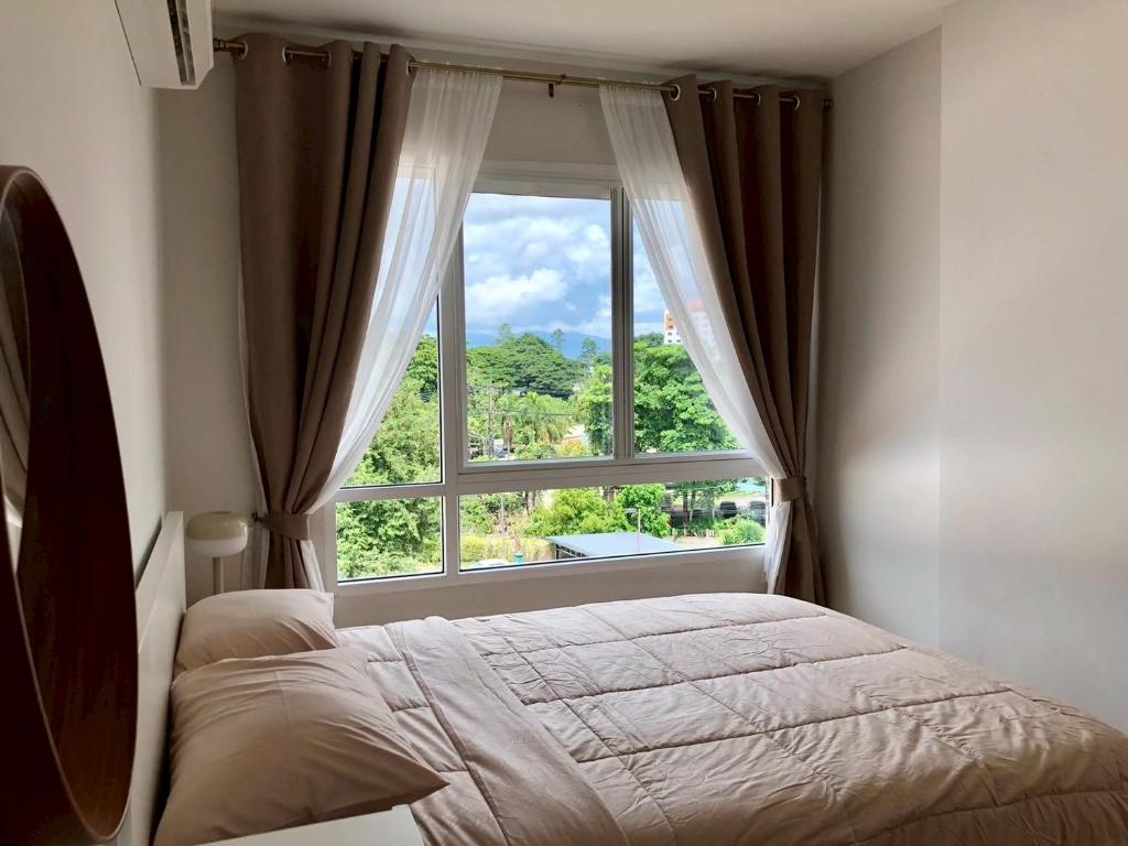 a bedroom with a bed and a large window at Kalpapruek Grand Park near Central Plaza Pool&Gym in Ban San Ton Ko (1)
