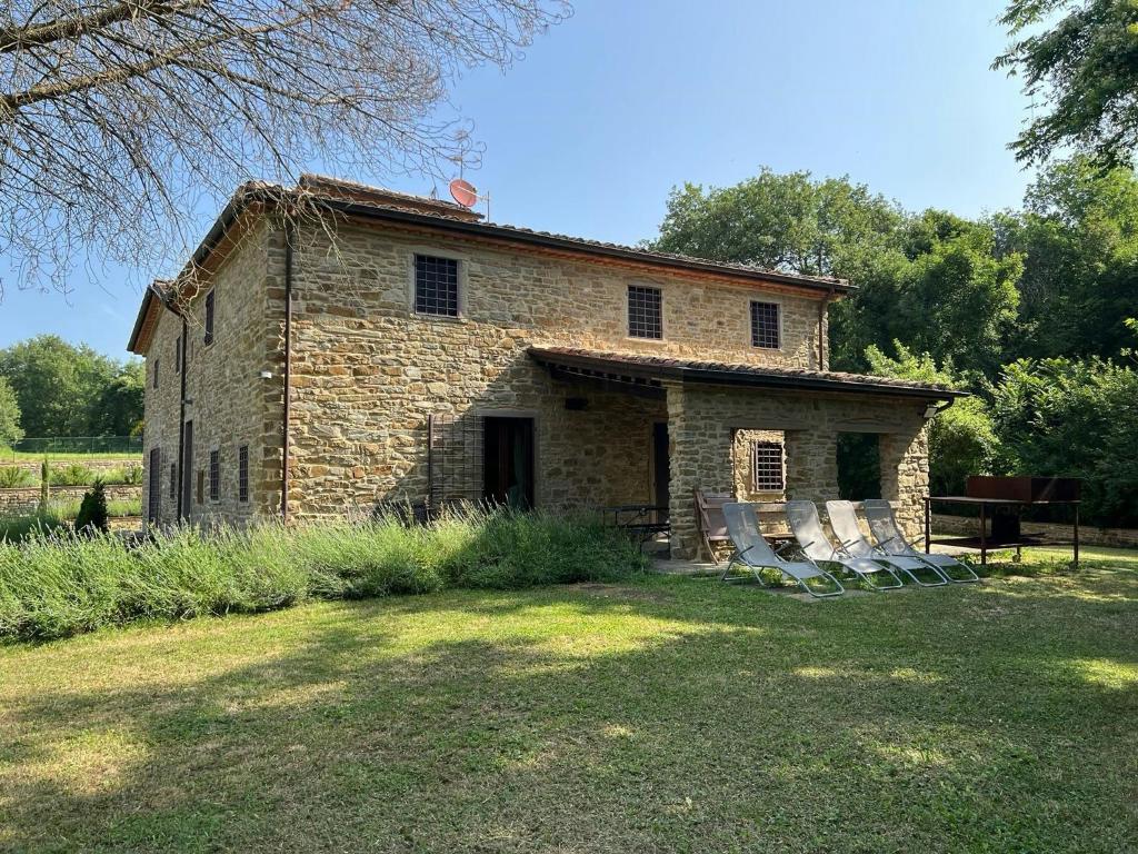 an old stone house with chairs in the yard at Rustico Restaurato Sulle Colline Di Arezzo in San Polo