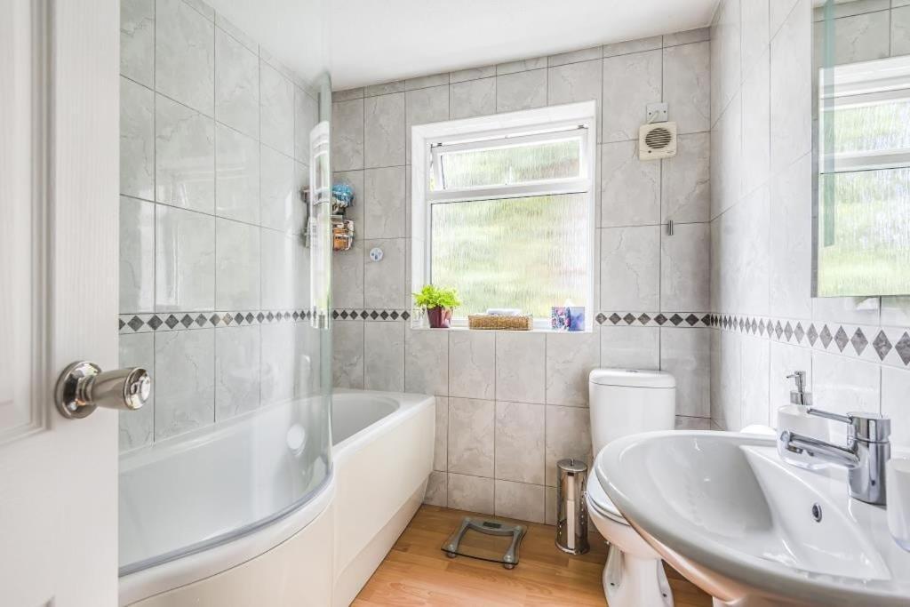 a white bathroom with a tub and a sink at Large Central Lodge Near Heathrow Airport & London with Parking in Langley Station