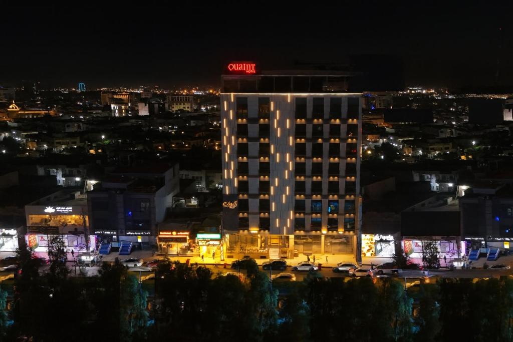 Un edificio iluminado con un letrero de neón en la parte superior. en Quaint Hotel Erbil, en Erbil