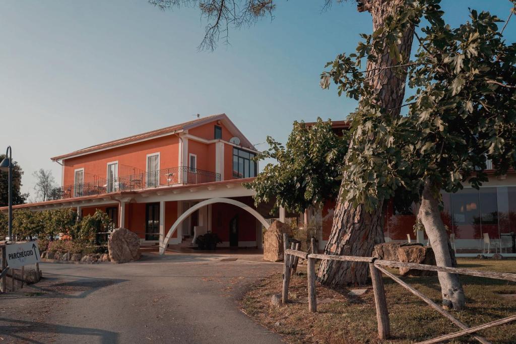 Un edificio naranja con un árbol delante. en Terra di Vento, en Montecorvino Pugliano