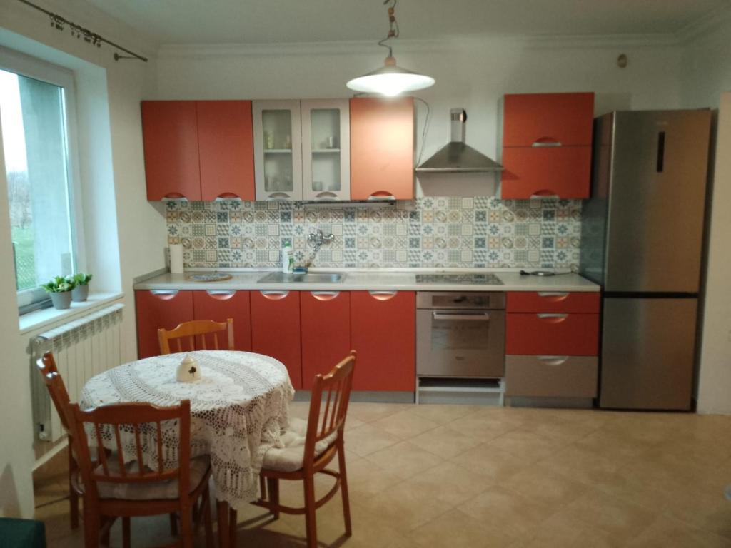 eine Küche mit roten Schränken und einem Tisch mit Stühlen in der Unterkunft U bram Podbeskidzia in Ligota