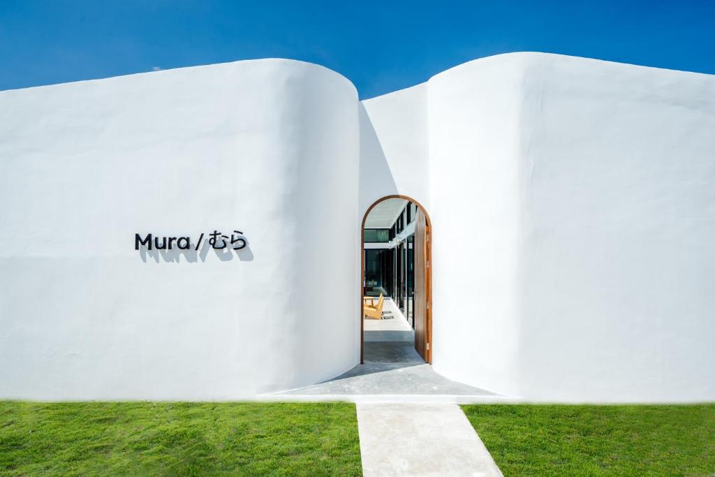 un bâtiment blanc avec une porte dans l'herbe dans l'établissement EL MAR Pool Villa, à Ban Bo Fai (1)