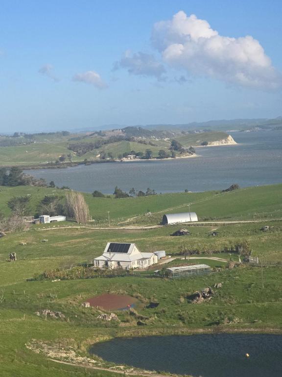 a farm in a field next to a body of water at lindum Grange in Maungaturoto