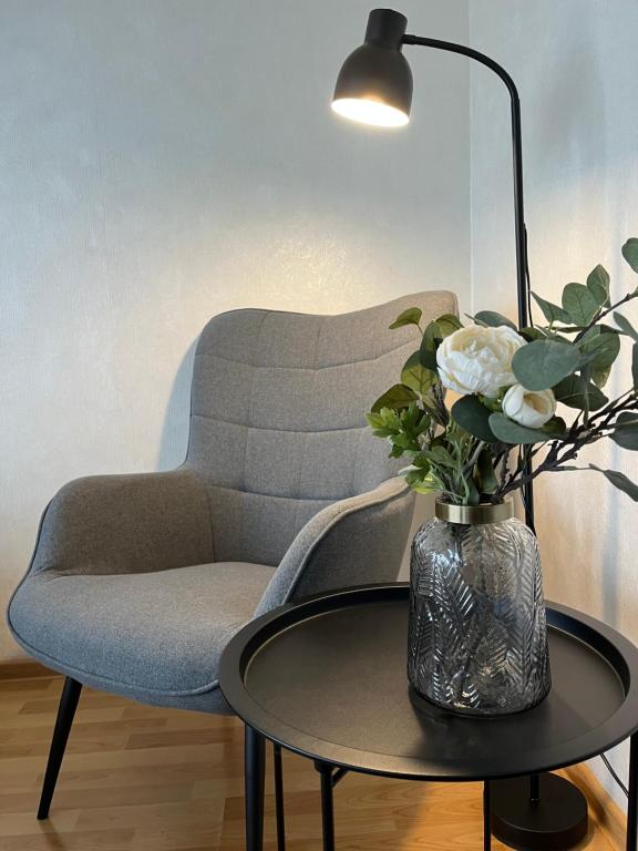 un vase de fleurs sur une table à côté d'une chaise dans l'établissement Maxima apartments, à Daugavpils