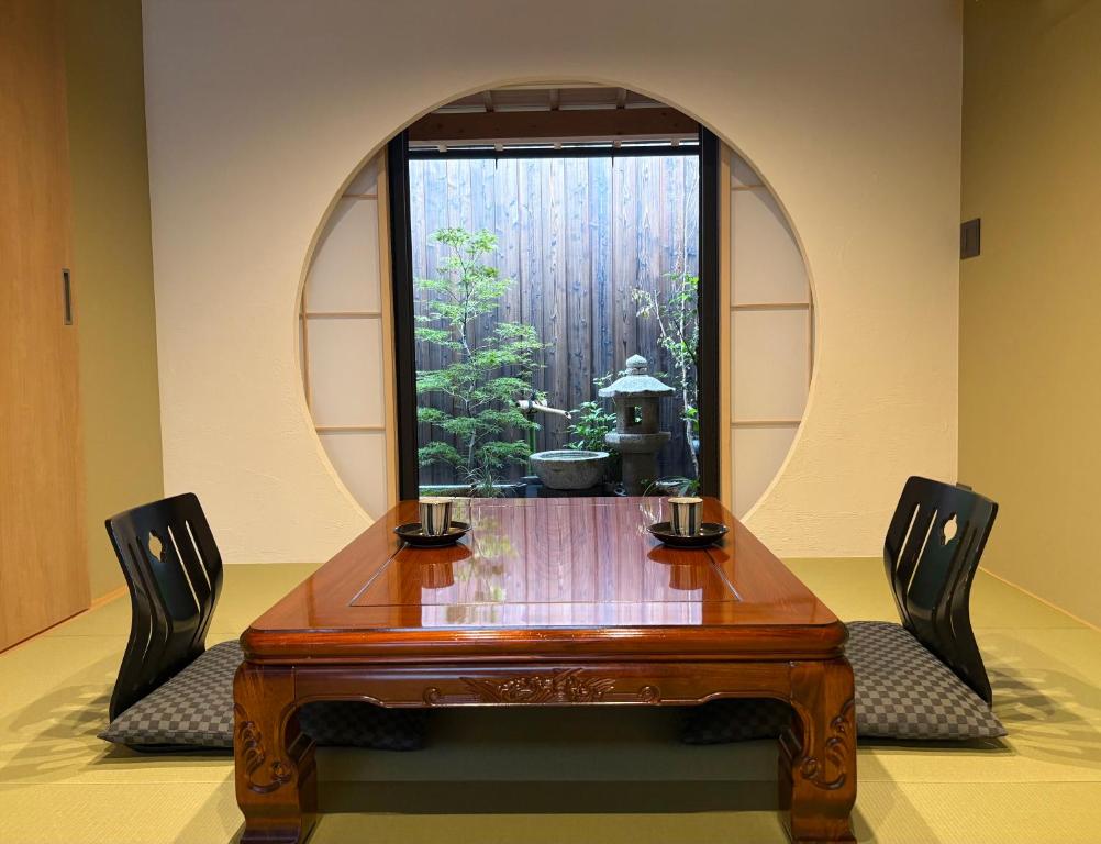 a wooden table with two chairs and a window at Machiya inside Chomoji temple, near Gion, downtown in Shimmachidōri