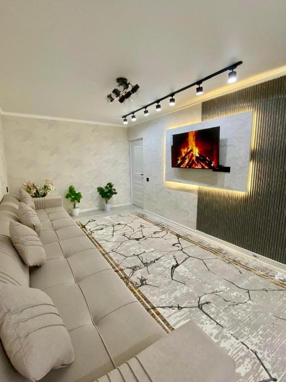 a living room with a couch and a fire on the wall at Appartament Shymkent in Shymkent