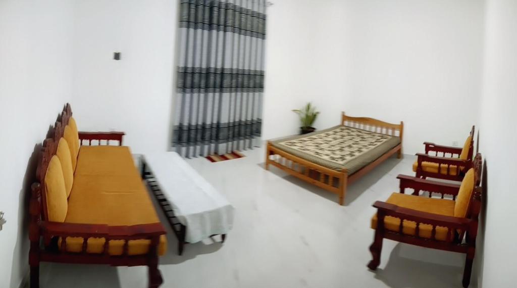 a living room with a bed and two chairs at Village Inn in Daulagala