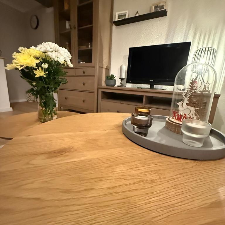 a table with a vase of flowers and a tv at Ferienwohnung SüntelLoft in Hameln