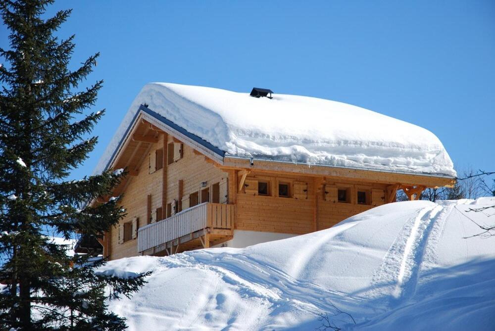 une cabane en rondins avec un toit recouvert de neige dans l'établissement Grand Chalet au Praz de Lys, à Taninges