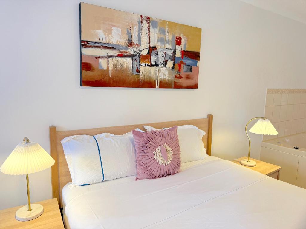 Un dormitorio con una cama blanca con dos lámparas. en Beachcomber Motel & Apartments, en Apollo Bay