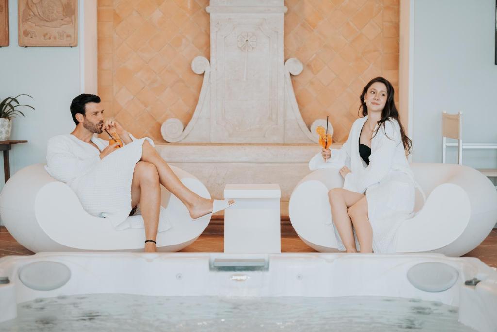 a man and woman sitting in inflatable chairs in a pool at Locanda Poggioleone in Castiglione del Lago