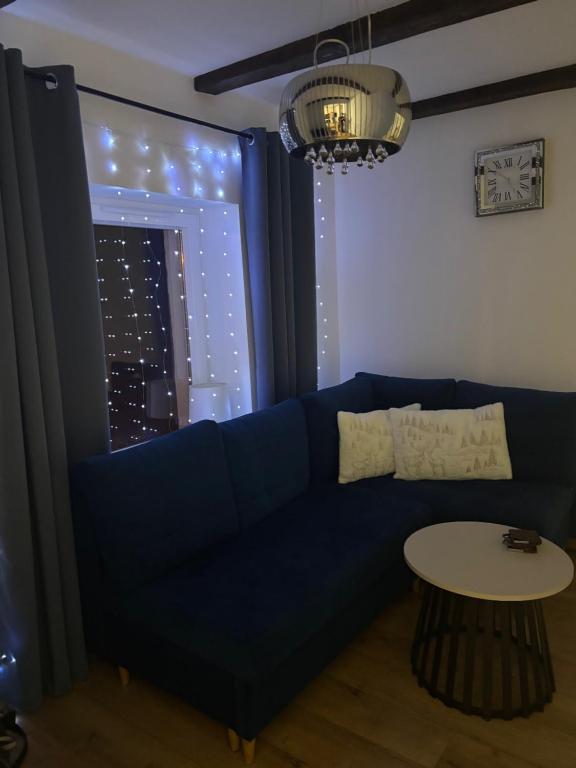 Una sala de estar con un sofá azul y una mesa. en Apartament Gołębiewscy, en Boguszów-Gorce