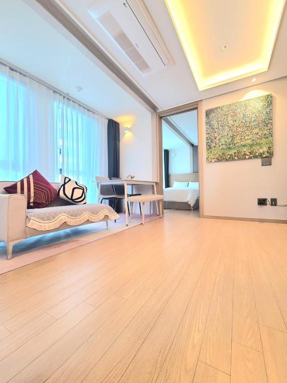 a living room with a couch and a painting on the wall at Haeundae Elbon the Stay in Busan