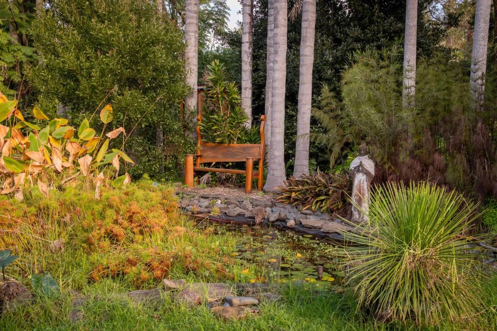 Totara NorthSub Tropical Paradise Retreat的木凳坐在树木繁茂的花园中