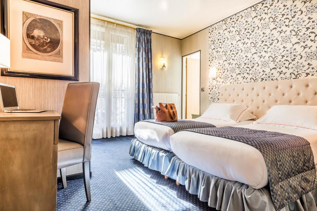 a hotel room with two beds and a desk at Hotel Regence Paris in Paris