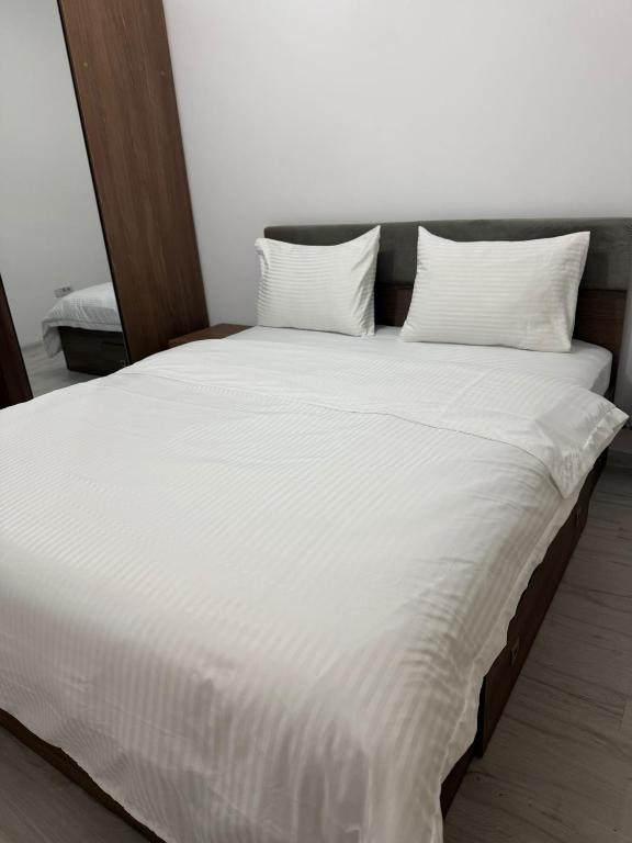 a large white bed with white sheets and pillows at Studio Militari Residence in Roşu