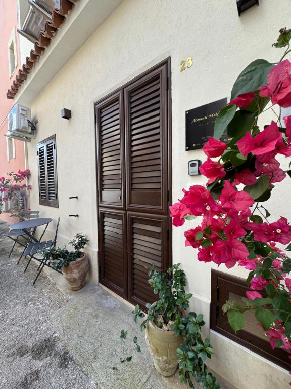 ein Gebäude mit einer Tür und rosa Blumen in der Unterkunft Manenti Holiday House in Noto
